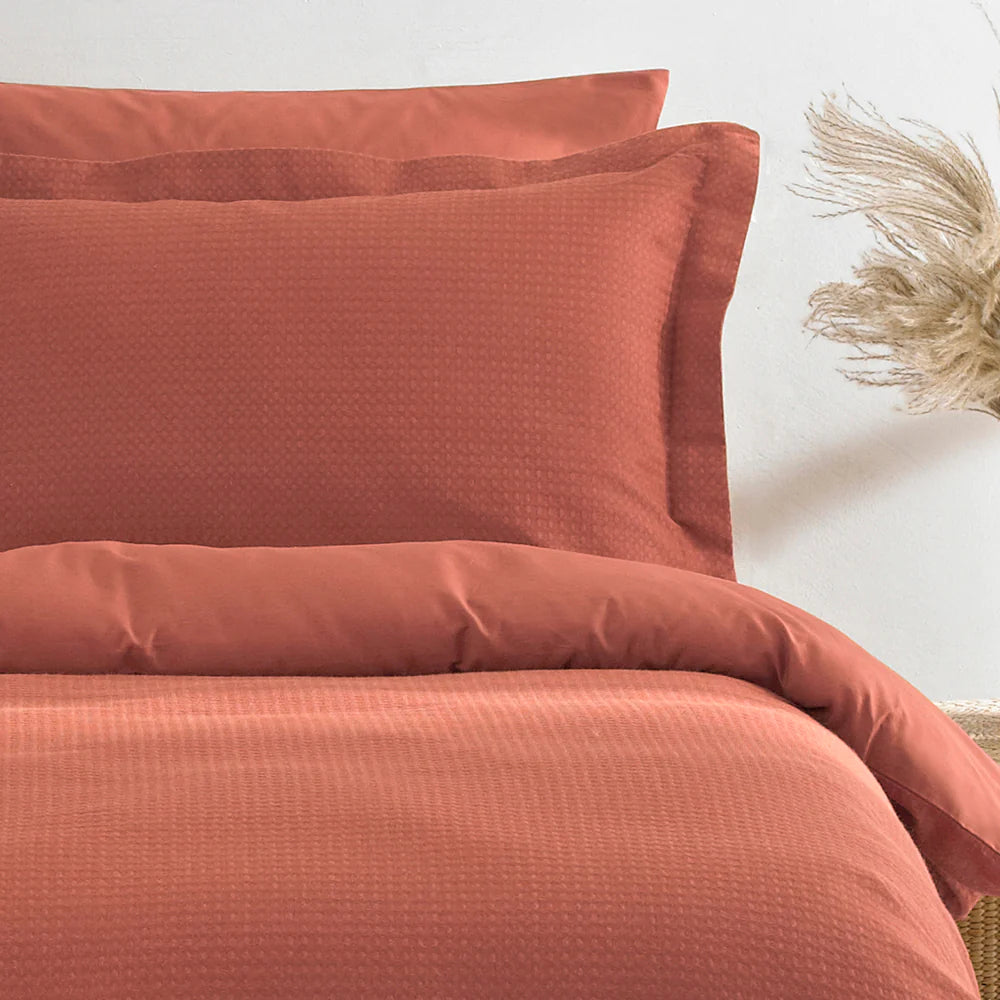A double duvet set in ginger color, displayed on a bed, with matching pillowcases on the bedside.