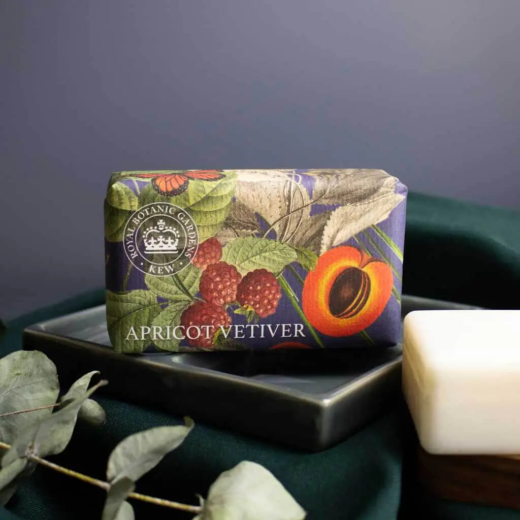 Bar of soap with decorative packaging featuring apricots and leaves on a dark surface.