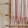 Beechwood Throw Camellia Striped pink and white towel draped over a wooden ladder against a neutral background