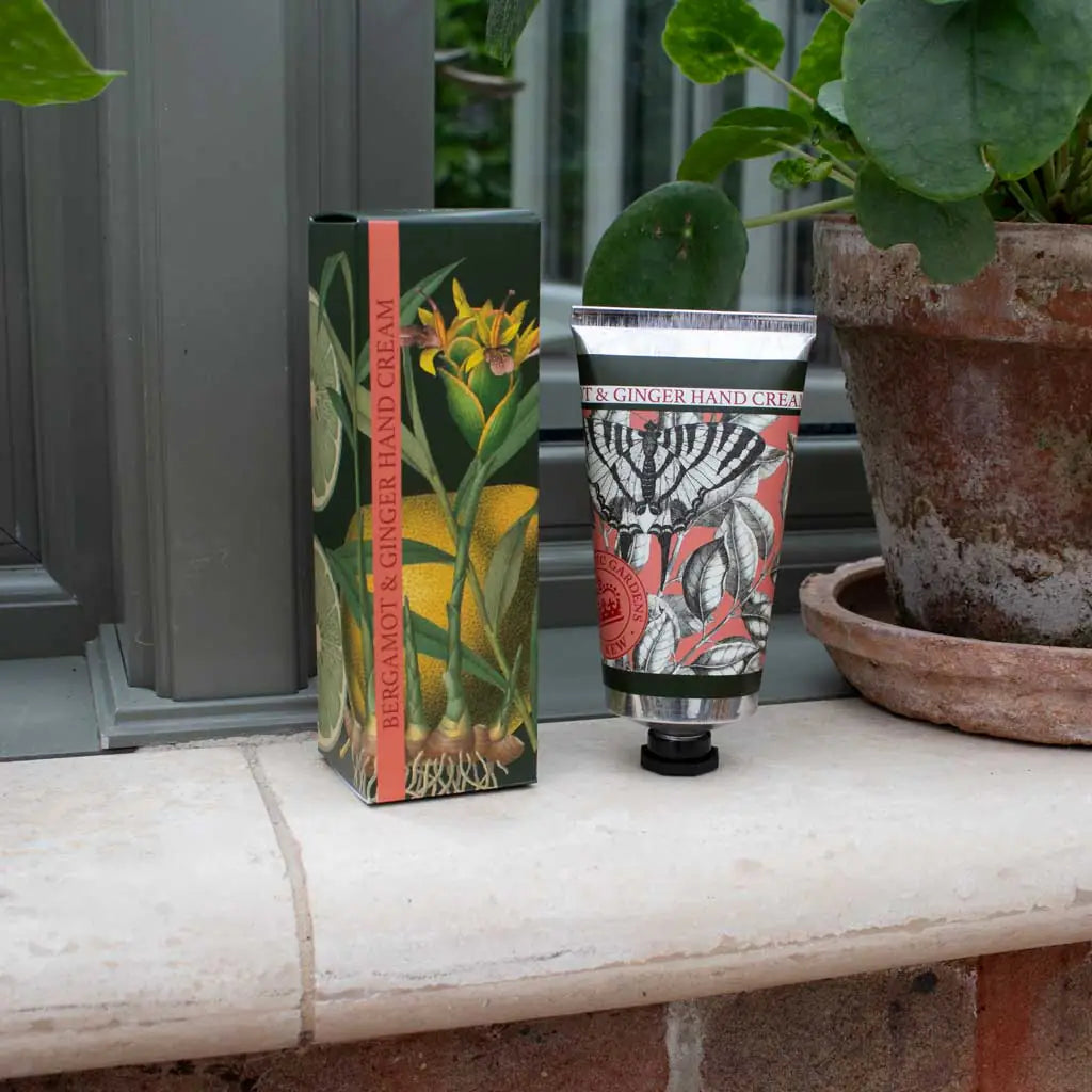 Hand cream packaging with decorative designs on a ledge with plants in the background