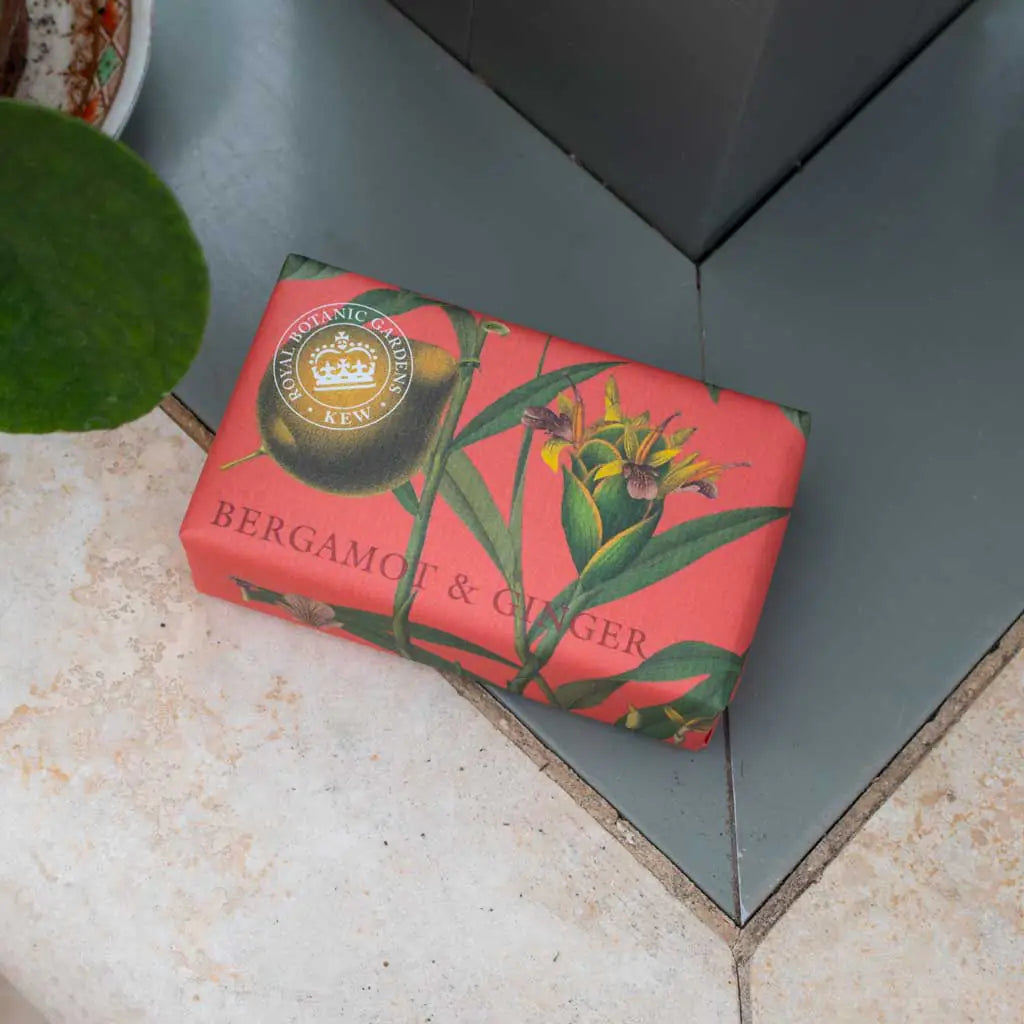 Bar of soap with a decorative red packaging featuring green leaves and flowers on a tiled surface.