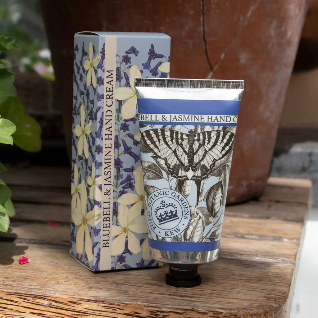 Bluebell & Jasmine hand cream and packaging on a wooden surface with plants in the background