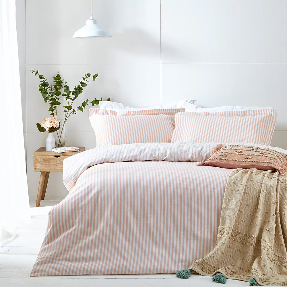 Bedroom with pink striped bedding and a wooden nightstand.