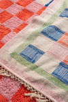 Colorful checkered fabric with a pattern of squares in red, pink, green, and blue.