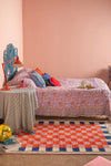 Bedroom with floral bedspread, colorful rug, and decorative pillows.