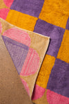 Close-up of a colorful geometric-patterned rug with pink, purple, and orange colors.
