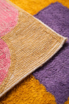 Close-up of a textured rug with geometric pattern on a multicolored background