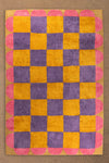 Checkered towel with pink, yellow, and purple squares on a beige background