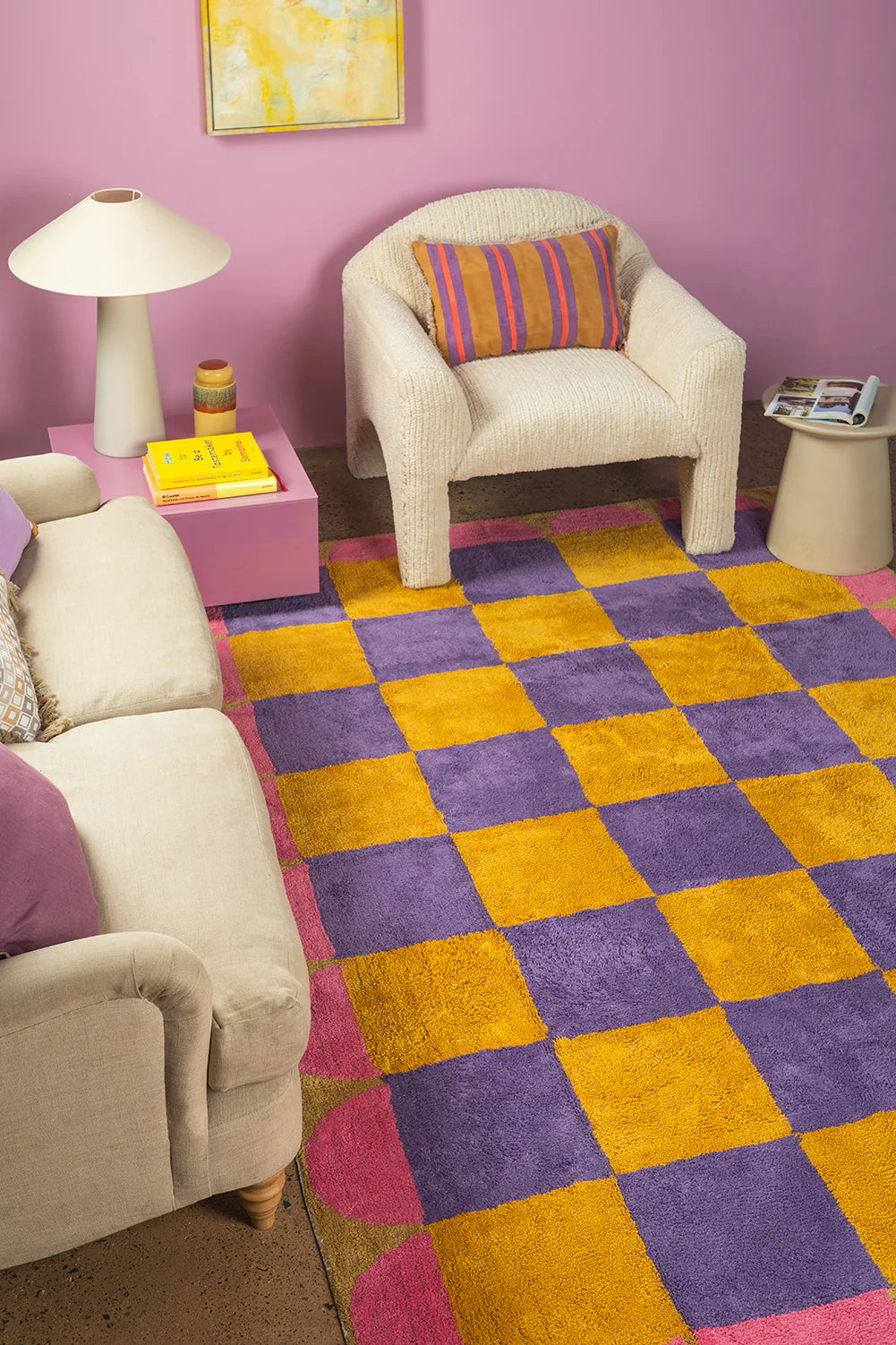 Living room with checkered purple and yellow rug, beige chairs, and a purple wall.