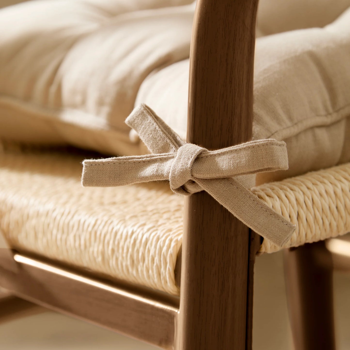 Close-up of a chair with woven seat and wooden frame, featuring a decorative ribbon.