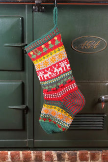  Knitted Christmas stocking with festive patterns hanging on a green Aga range cooker.