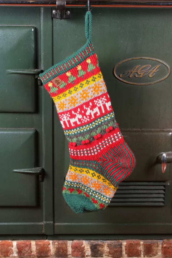 Knitted Christmas stocking with festive patterns hanging on a green Aga range cooker.