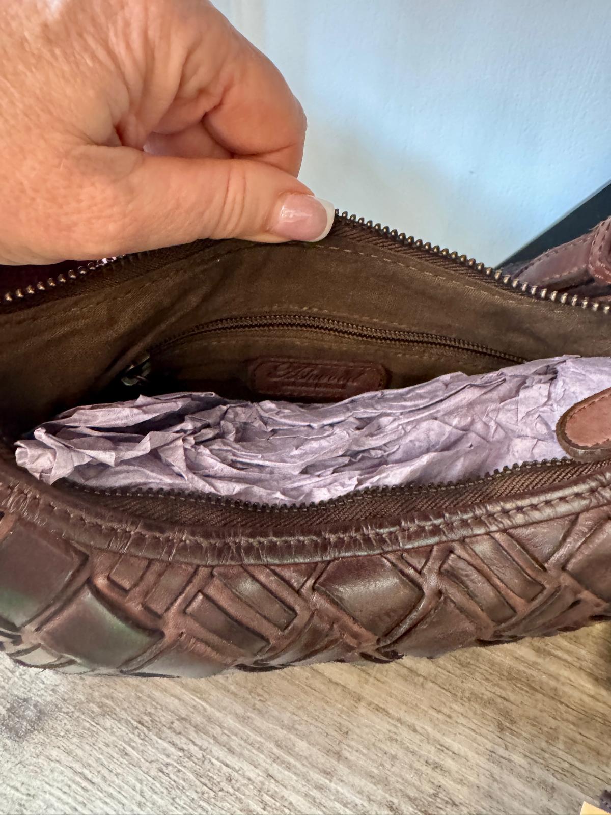 Brown leather bag with a textured pattern on a wooden surface