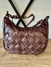 Brown woven handbag on a wooden surface with a neutral background