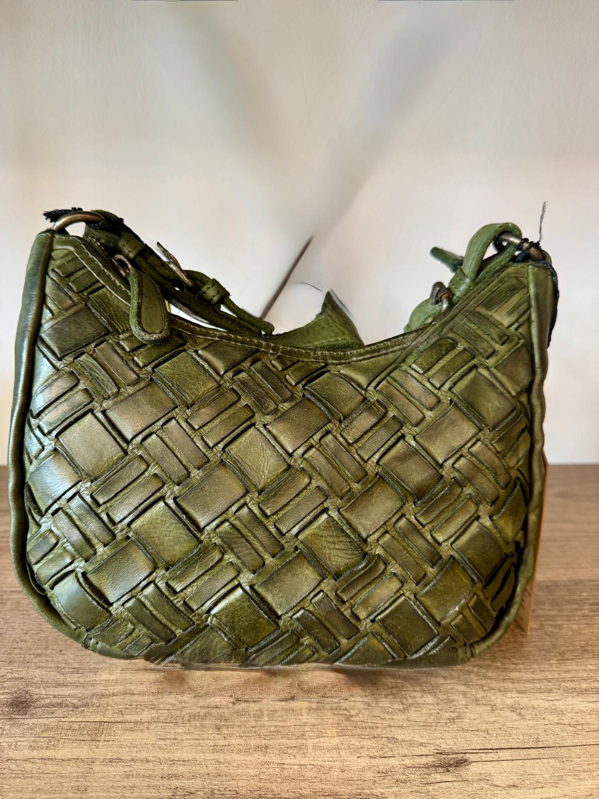 Green woven handbag on a wooden surface with a blurred background