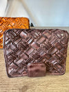 Brown woven leather clutch on a wooden surface