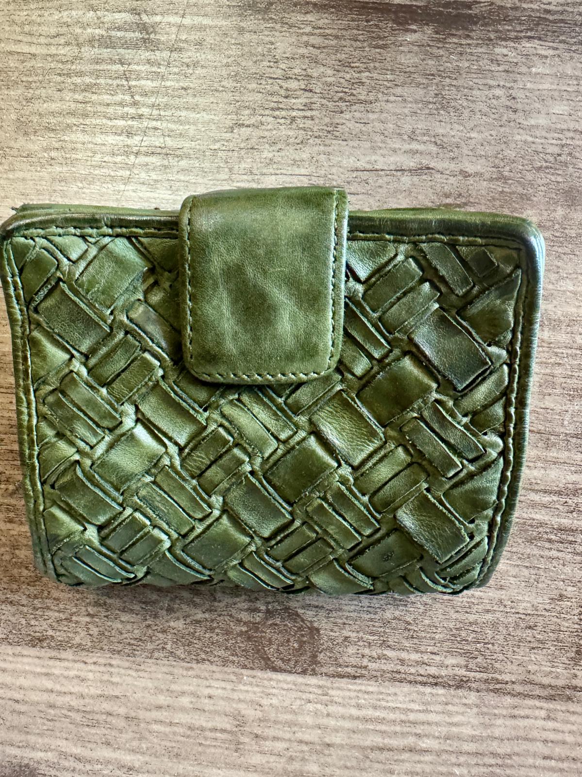 Green woven wallet on a wooden surface