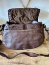 Brown leather handbag on a wooden surface with a white background