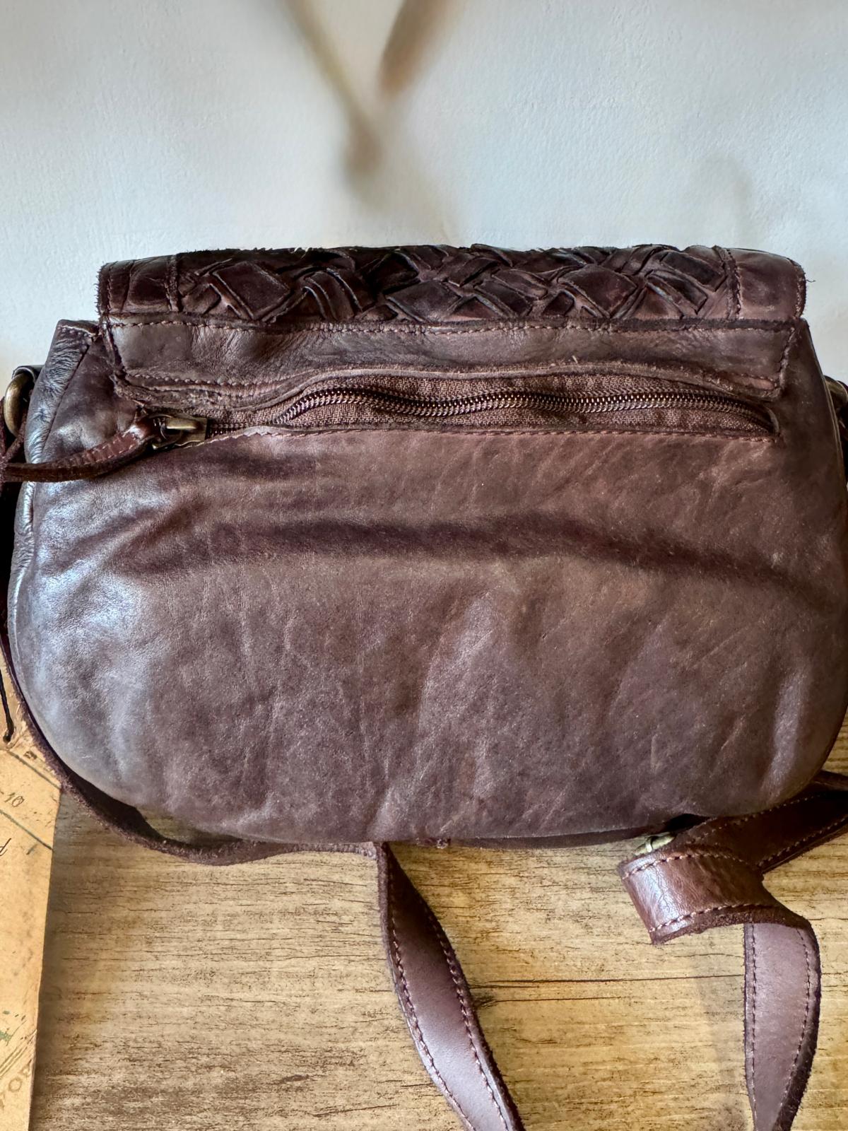 Brown leather handbag on a wooden surface