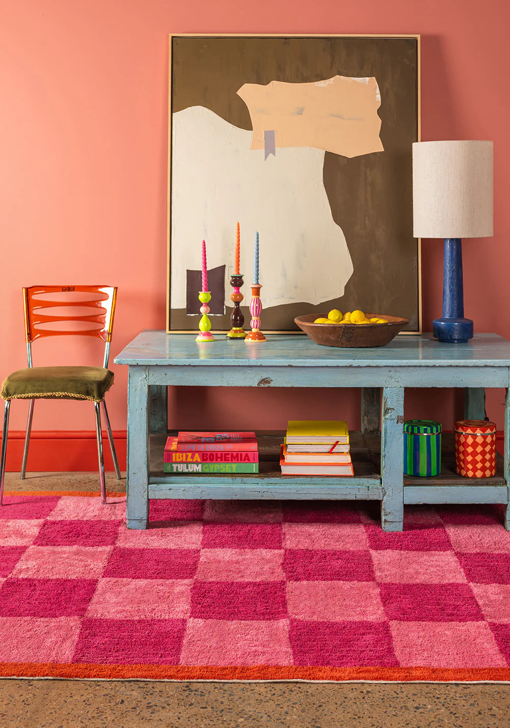 Living room with a pink checkered rug, blue table, and colorful decor