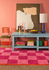 Living room with a pink checkered rug, blue table, and colorful decor