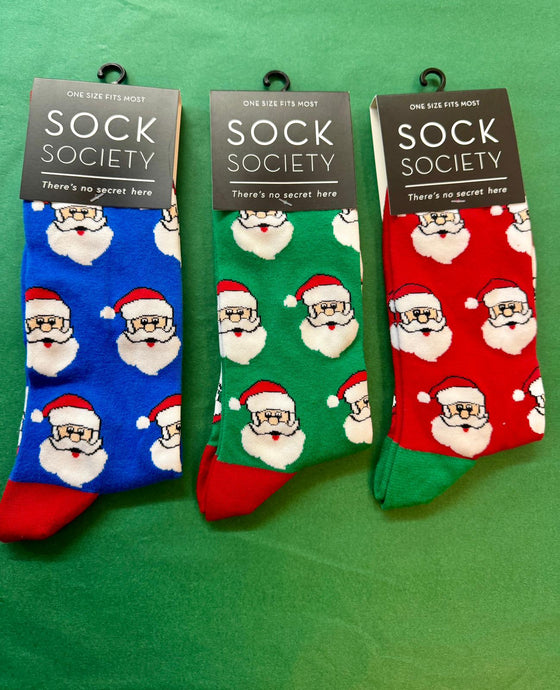 Three pairs of socks with Santa Claus patterns from Sock Society on a green background.